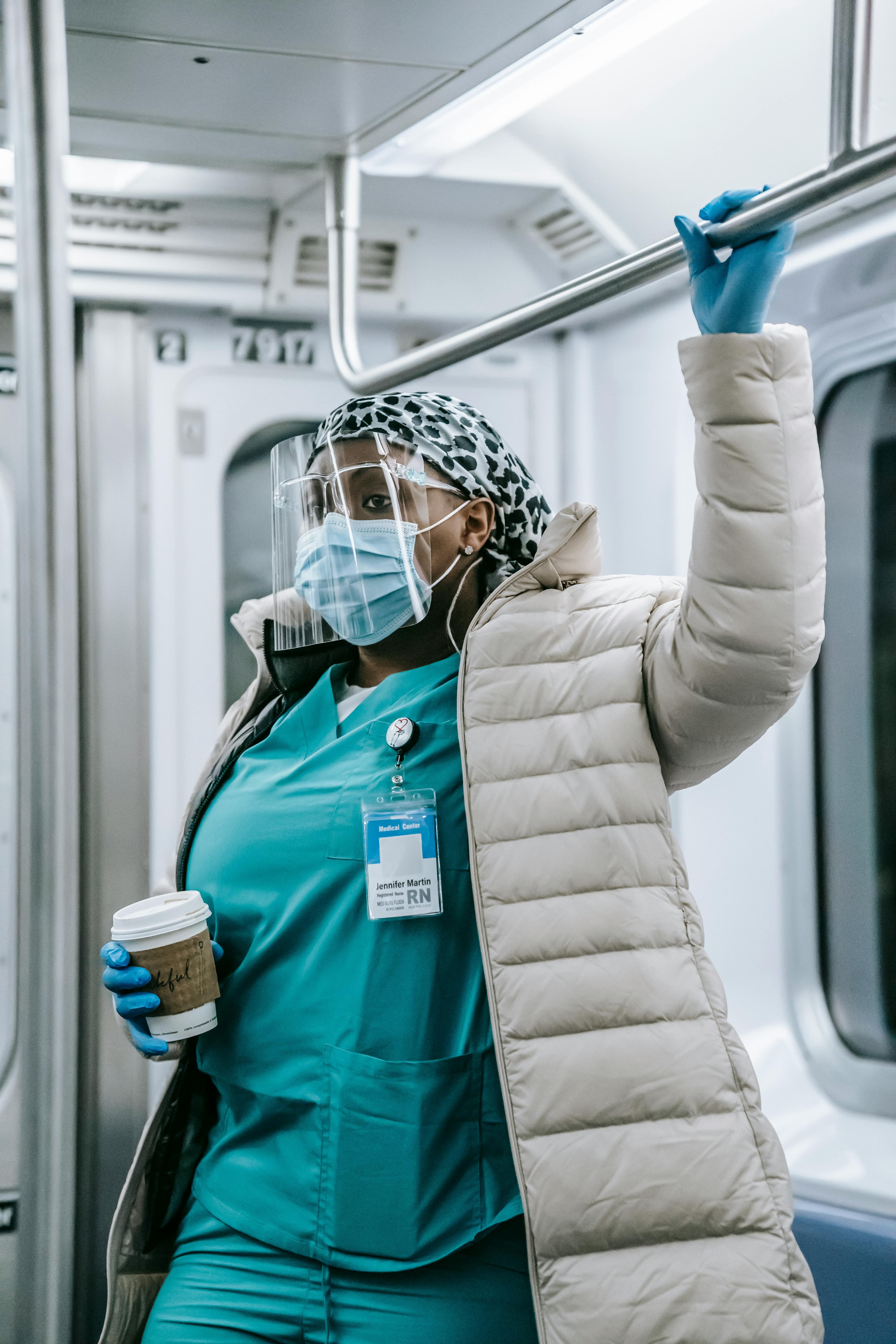 Nurse in teal scrubs on subway commute looking thoughtful