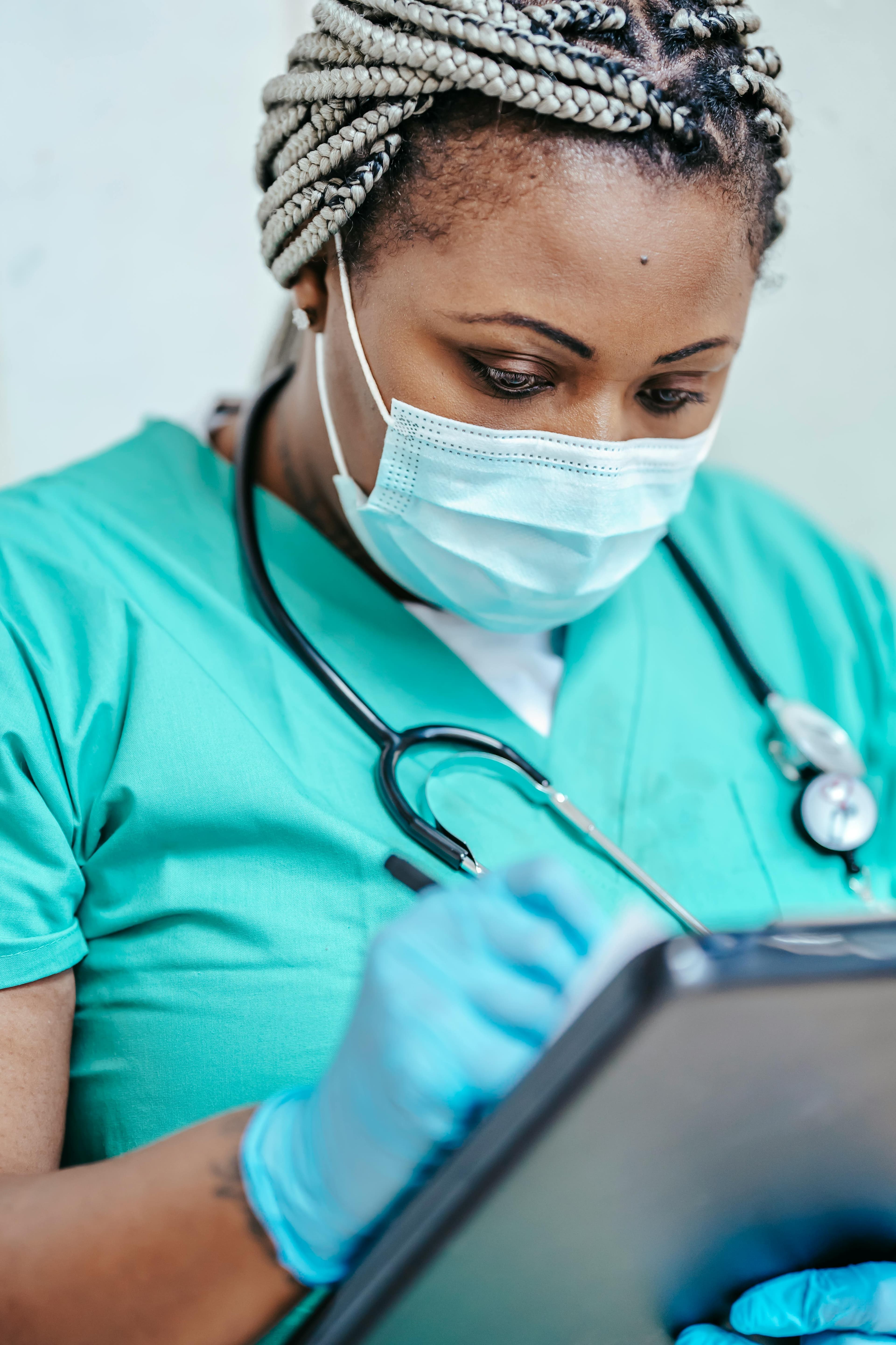 Nurse in green scrubs writing on clipboard