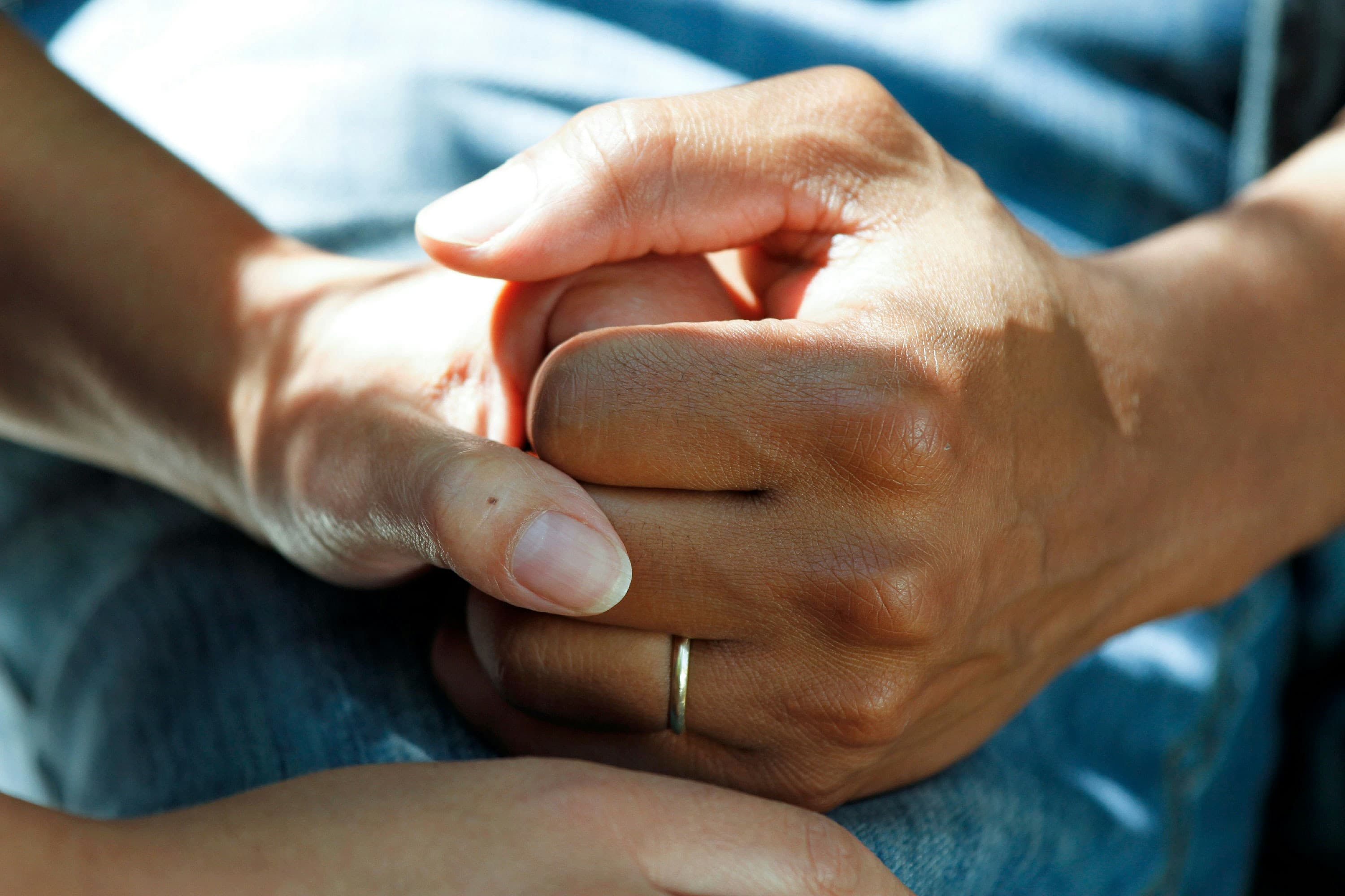 Close-up of hands being held on blue fabric